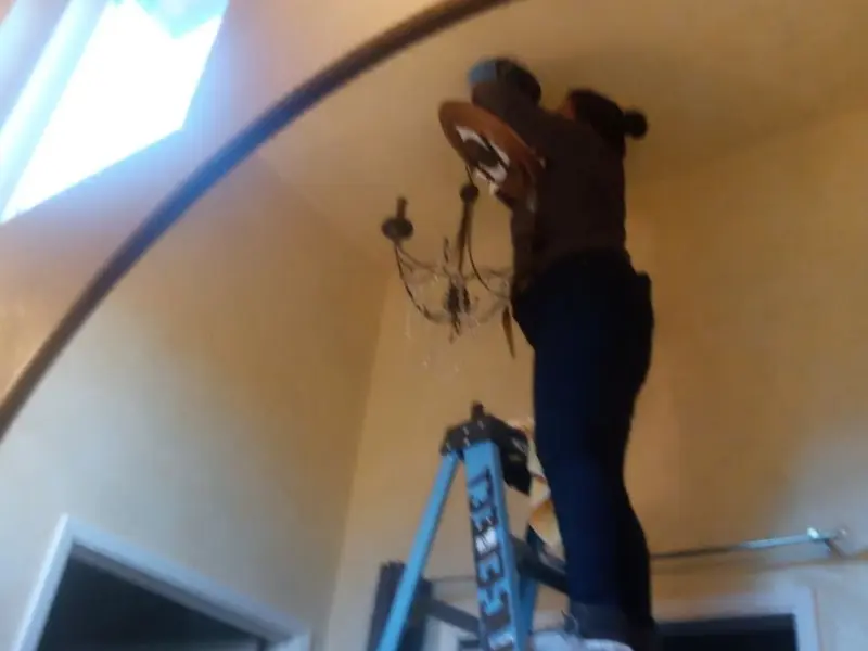 Electrician installing a chandelier in a Burns residence